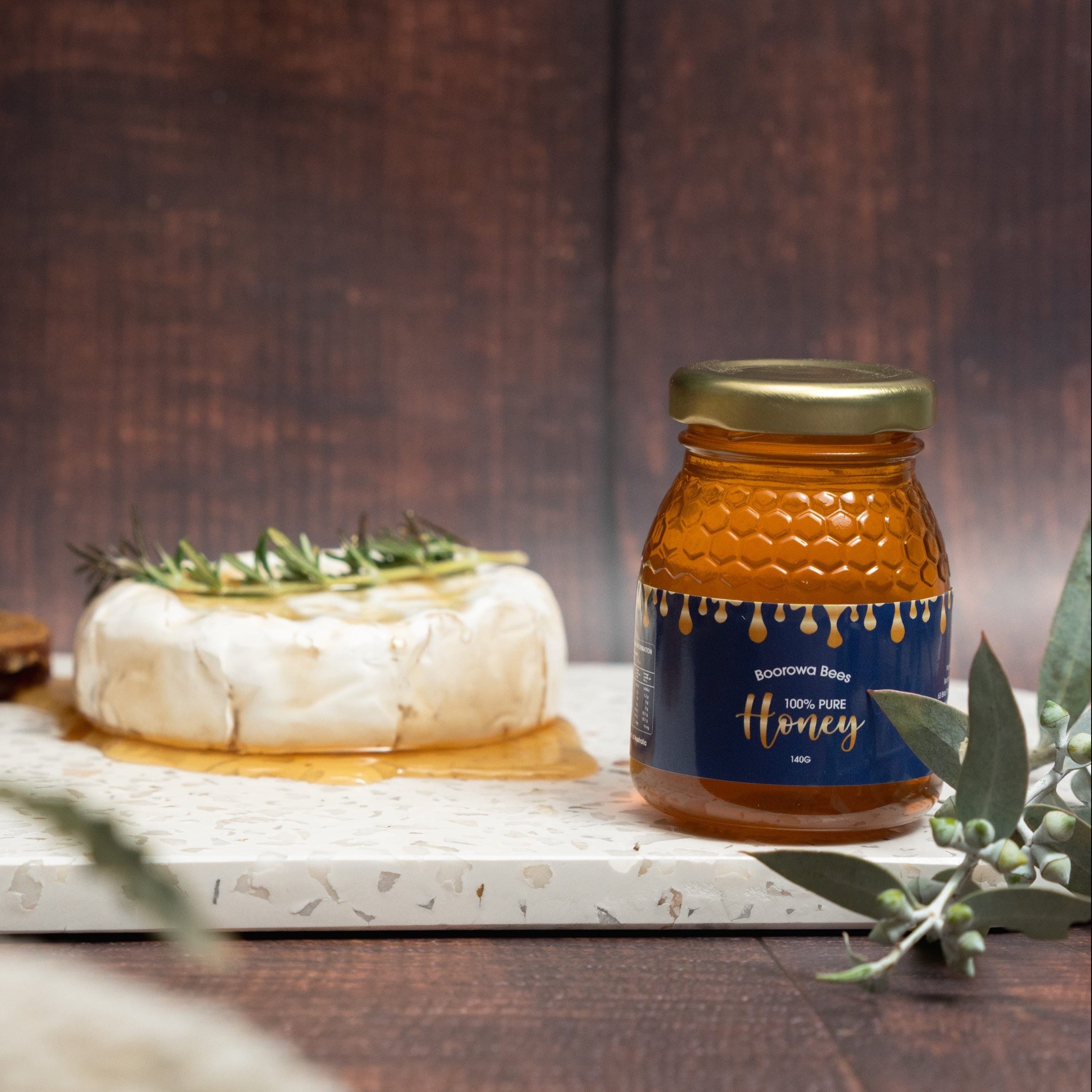 Jar of honey with honeycomb and cheese on a wooden table